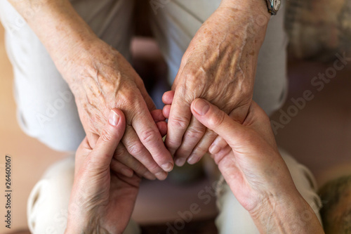 Fototapeta Naklejka Na Ścianę i Meble -  Nurse consoling her elderly patient by holding her hands