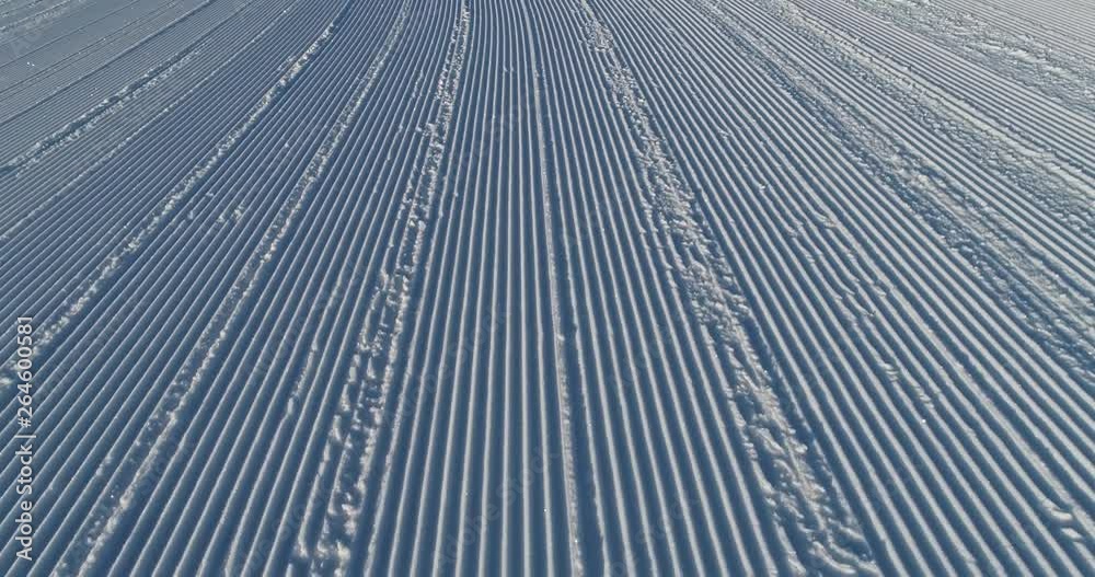 Flying over the ski slope on a frosty sunny day. Ski velvet, snow sparkles. Smooth parallel lines texture. 4K drone footage Flying over the ski slope on a frosty sunny day. Ski velvet, snow sparkles. Smooth parallel lines texture. 4K drone footage