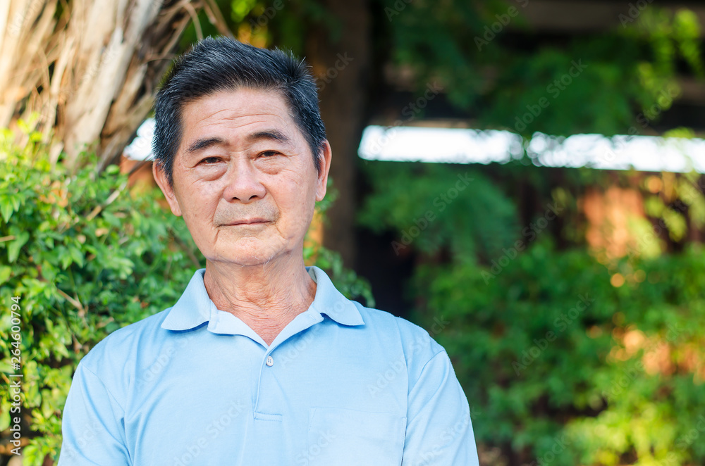 Happy asian senior gentleman sitting on a wooden bench and relaxing in a park on a sunny day Happy asian senior gentleman sitting on a wooden bench and relaxing in a park on a sunny day