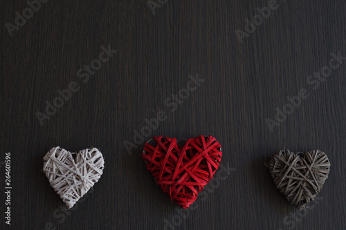 Red, grey and white wicker hearts on wooden background