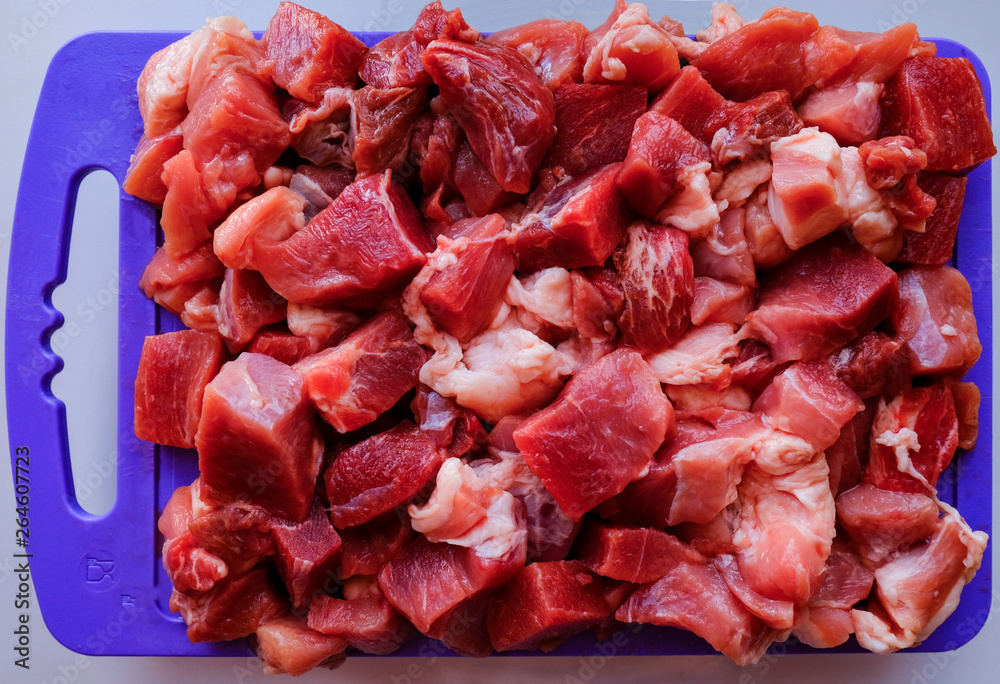 diced pork meat with layers of fat lies on a purple cutting board