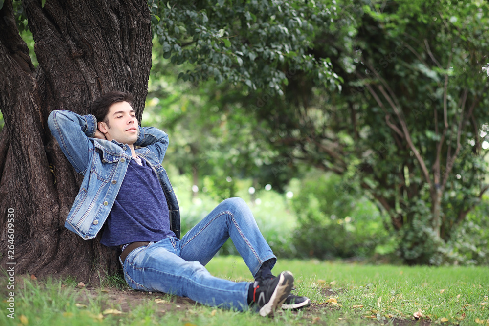 A young man walks in the park at lunch time. A man is on a walk in the city. A student in the park.