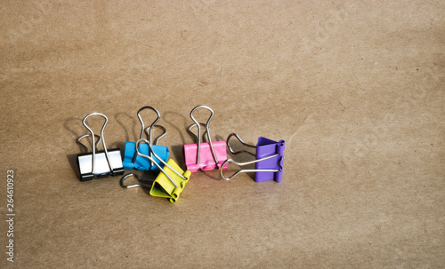 Clips for paper of different colors on the background of rough brown kraft paper. Stationery. With copy space for text.