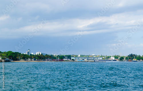 View of the port of Santo Domingo Dominican Republic from Juan Baron square, with beautiful sunny day and blue waters with boats arriving at port.