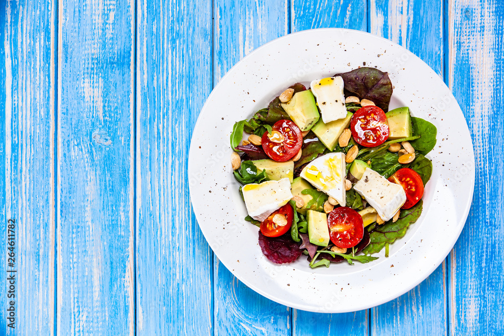 Salad with avocado and cheese on wooden background
