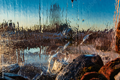 Blurred image formed by a falling wall of water. A variety of water figures in the waterfall. Translucent background of multicolor abstract aqua image.