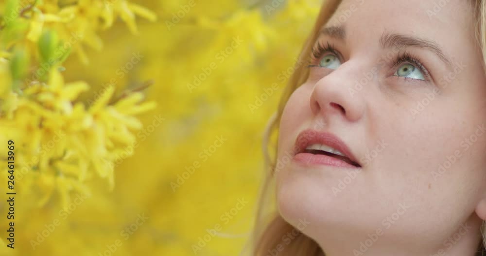 Cute woman taking in the sweet scent of a yellow blooming tree Cute woman taking in the sweet scent of a yellow blooming tree