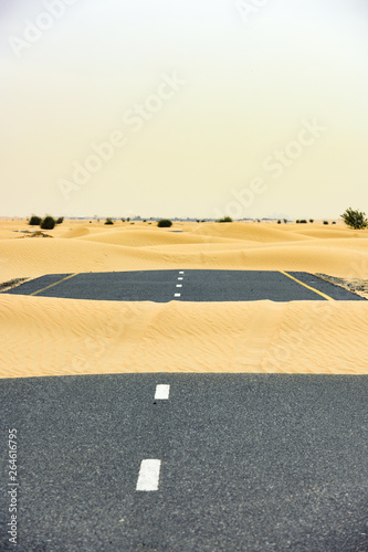  Selective focus  Stunning view of a deserted road covered by sand dunes. Empty road that run through the Dubai desert during sunset. Dubai  United Arab Emirates   UEA 