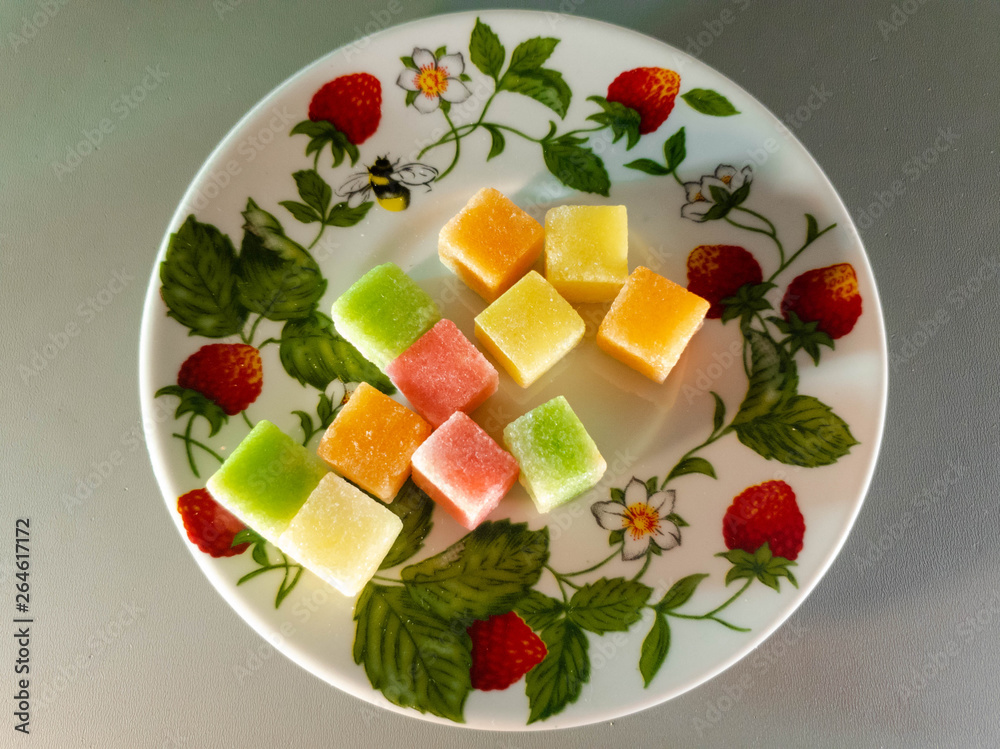Colored fruit sugar cubes on a plate. Fruit sugar. Colored fruit sugar cubes on a plate. Fruit sugar.