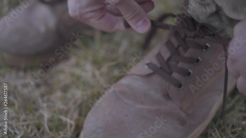 Military man in uniform tying brown shoelaces on military boots and going to protect motherland. Close-up. photo