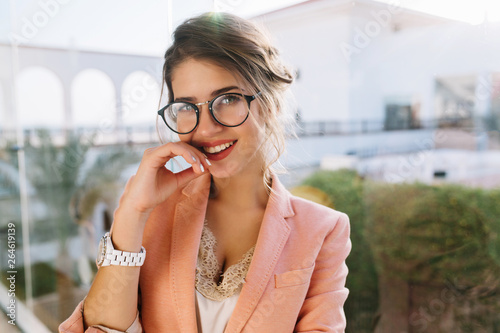 Billede på lærred Closeup portrait of young gorgeous girl in stylish glasses, pretty student, business woman wearing elegent pink jacket, beige blouse with lace, day makeup
