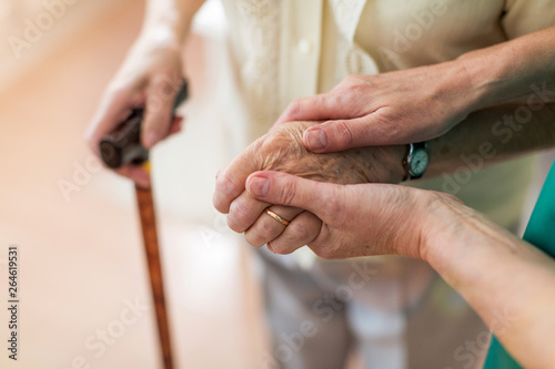 Nurse consoling her elderly patient by holding her hands photo