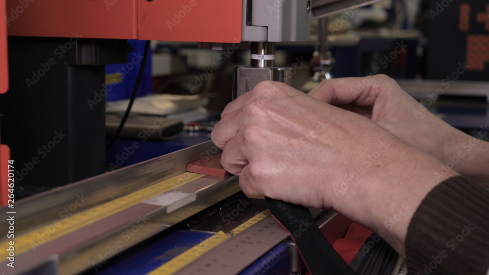 In a slow motion video in a garment factory, women press (cut) various pieces of clothing and fabric locks and various materials using different machines. Concept of: Work, Factory, Seamstress. In a slow motion video in a garment factory, women press (cut) various pieces of clothing and fabric locks and various materials using different machines. Concept of: Work, Factory, Seamstress.