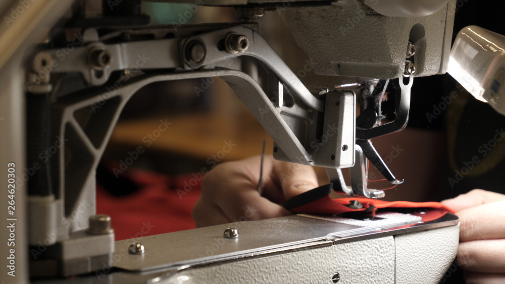 A seamstress in a seamstress factory (at home) sews clothes from fabric materials. Using a sewing machine in slow motion. Concept of: Factory, Work, Labor, Cloth, People, Macro, Clothes. A seamstress in a seamstress factory (at home) sews clothes from fabric materials. Using a sewing machine in slow motion. Concept of: Factory, Work, Labor, Cloth, People, Macro, Clothes.