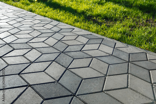 The footpath in the park is paved with diamond shaped concrete tiles.