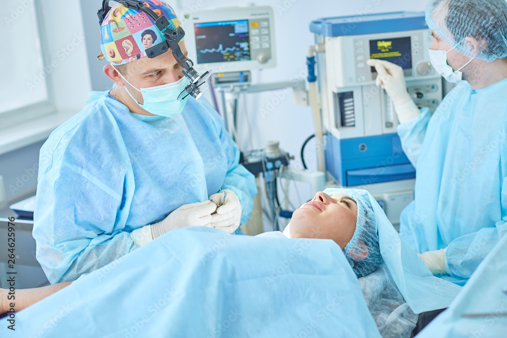 Several doctors surrounding patient on operation table during their work. Team surgeons at work in operating room Several doctors surrounding patient on operation table during their work. Team surgeons at work in operating room