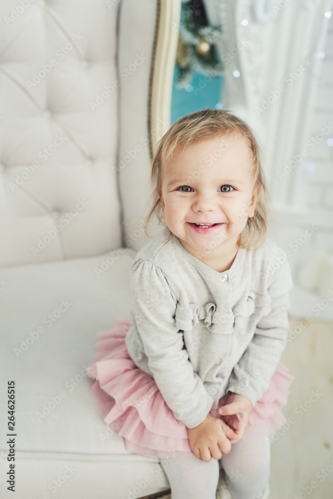 cute little child sitting in chair near Christmas tree. Happy new year. Portrait little girl. Christmas concept. cute little child sitting in chair near Christmas tree. Happy new year. Portrait little girl. Christmas concept.