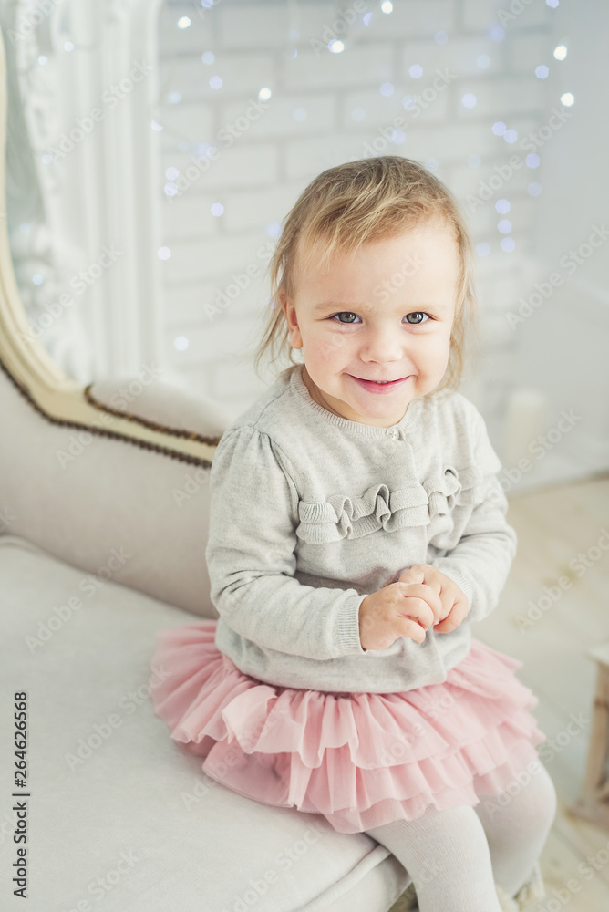 cute little child sitting in chair near Christmas tree. Happy new year. Portrait little girl. Christmas concept. cute little child sitting in chair near Christmas tree. Happy new year. Portrait little girl. Christmas concept.