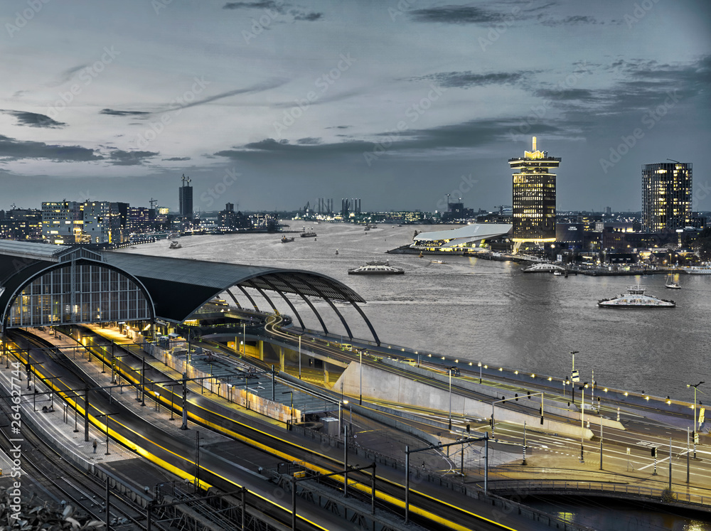 Black and white image of Amsterdam city center with central station, modern architecture and river  with yellow accents