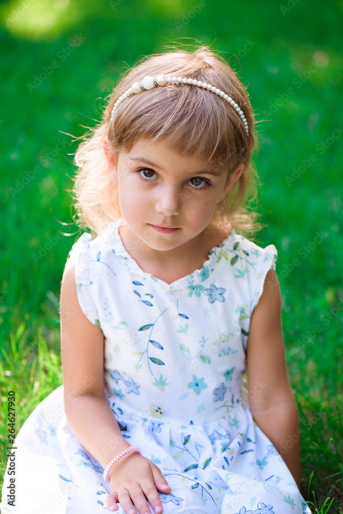 Portrait of a smiling little girl sitting on green grass. Portrait of a smiling little girl sitting on green grass.