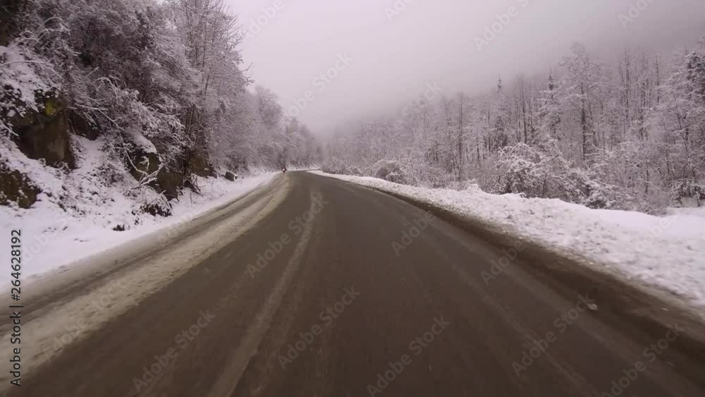 Driving the Colibita Road in winter with slick icy conditions. Fog hangs over trees along a frigid river with a small bridge crossing. Motorcycle on a snowy road. Driving the Colibita Road in winter with slick icy conditions. Fog hangs over trees along a frigid river with a small bridge crossing. Motorcycle on a snowy road.