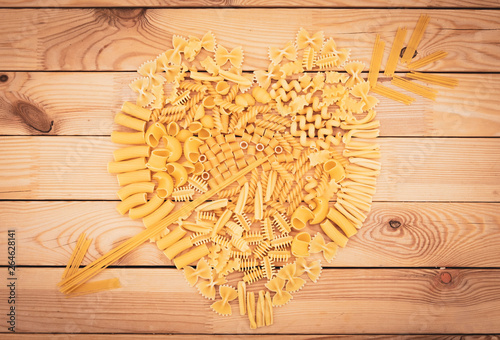 Big heart made with different kind of pasta. Natural wooden table as background. No people.