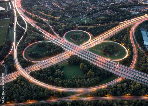 Aerial long exposure of highway node with overpasses and curves illuminated by car lights during rush hour traffic 