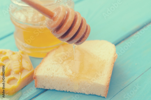 Honey and honey accessories for its use on a blue wooden background.
