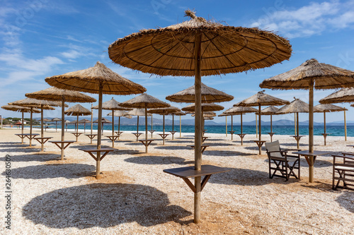 Sun parasols at empty Mati beach in a spring sunny day 