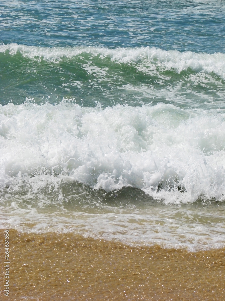 White waves crashing and splashing with foam near the shore in the sun on the ocean for the background. White waves crashing and splashing with foam near the shore in the sun on the ocean for the background.
