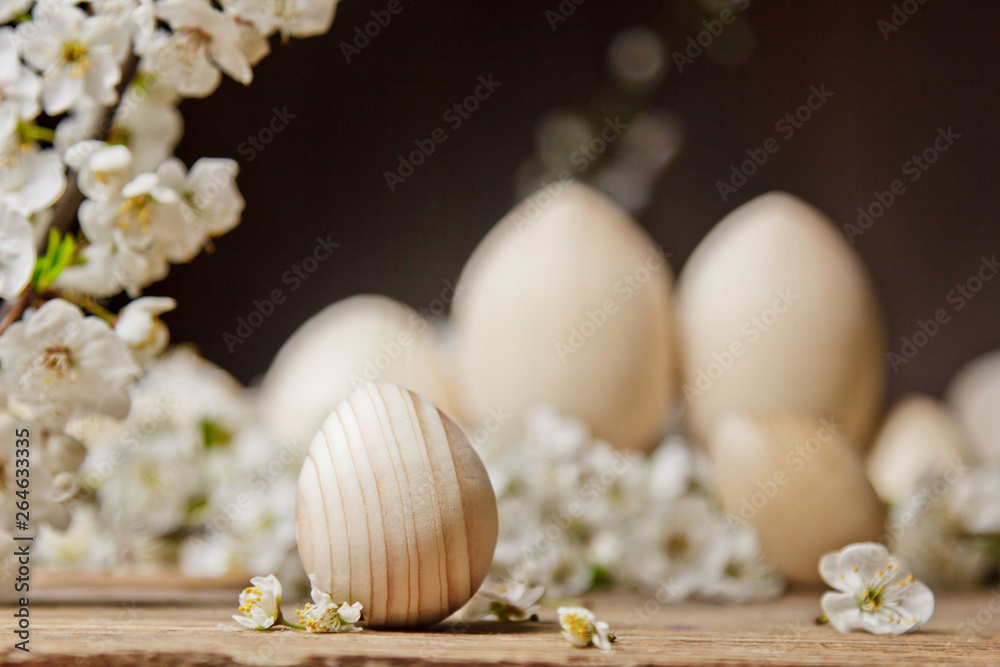 wooden easter eggs among flowering cherry branches on a rustic table. symbolic composition of the spring holiday for a gift card. copy space. close up. petals of white flowers. the rebirth of nature wooden easter eggs among flowering cherry branches on a rustic table. symbolic composition of the spring holiday for a gift card. copy space. close up. petals of white flowers. the rebirth of nature