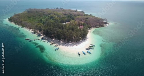 Beautiful aerial view of Gili Nanggu Island with white sand, boats, and turquoise water in Lombok near Bali, Indonesia. Shot in 4k resolution from a drone flying from right to left photo