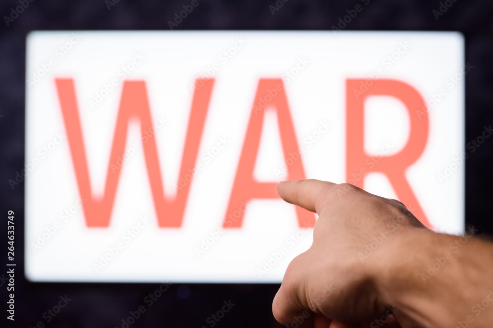 Young male pointing to a screen with inscription WAR to draw our attention to circumstances that different conflicts between countries can lead Young male pointing to a screen with inscription WAR to draw our attention to circumstances that different conflicts between countries can lead