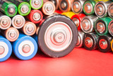Batteries of different types and sizes on red background