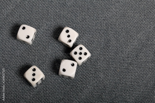 White dice with black markings. They lie on a surface covered with a coarse gray cloth. View from above.