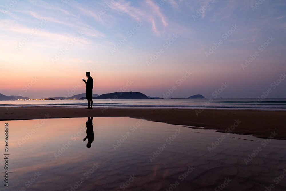 Venus and the silhouette of a man and their reflection on the background of the dawn on the beach of Sanya, Hainan Island, China