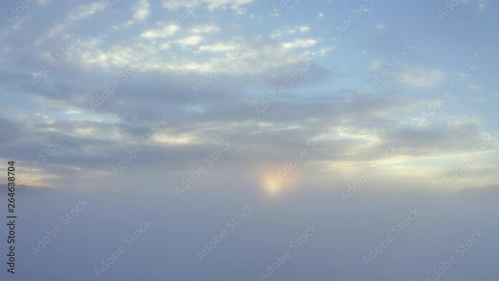 Exotic aerial sunrise view on foggy morning with silhouette of mountain peak and golden sunlight. Shot in 4k resolution from a drone flying upwards Exotic aerial sunrise view on foggy morning with silhouette of mountain peak and golden sunlight. Shot in 4k resolution from a drone flying upwards
