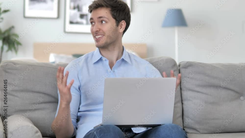 Online Video Chat on Laptop by Handsome Young Man Sitting at Creative Workplace Online Video Chat on Laptop by Handsome Young Man Sitting at Creative Workplace