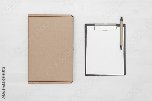 Blank cardboard parcel box and an empty invoice document mock up on a white table background.