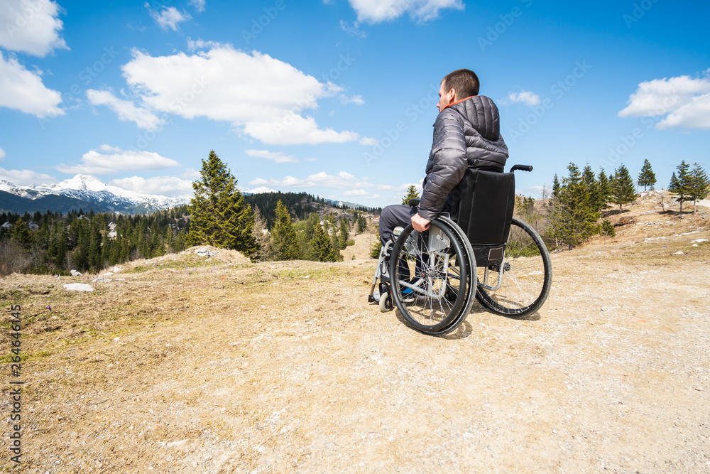 Εκτύπωση καμβά Wide angle photo ofYoung disabled man in wheelchair outside in nature observing