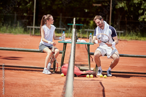 Guy and girl talking on tennis court © luckybusiness