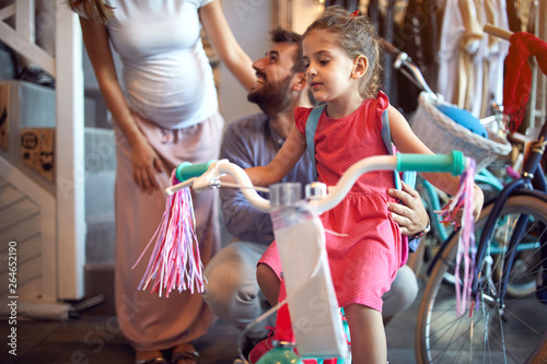 buying new bicycle for little girl in bike shop .