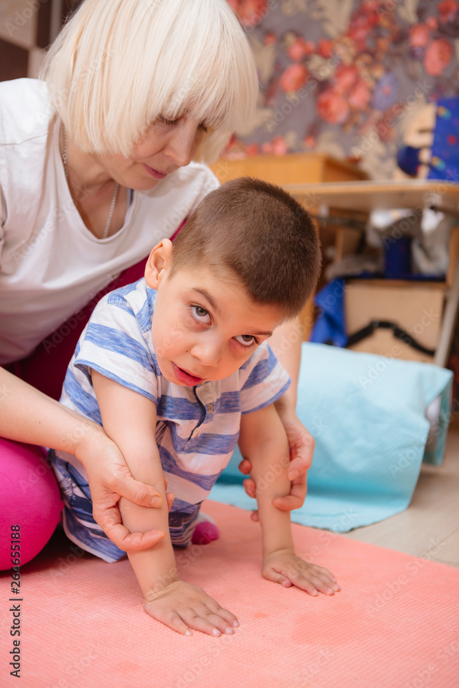 little kid with cerebral palsy has musculoskeletal therapy by doing