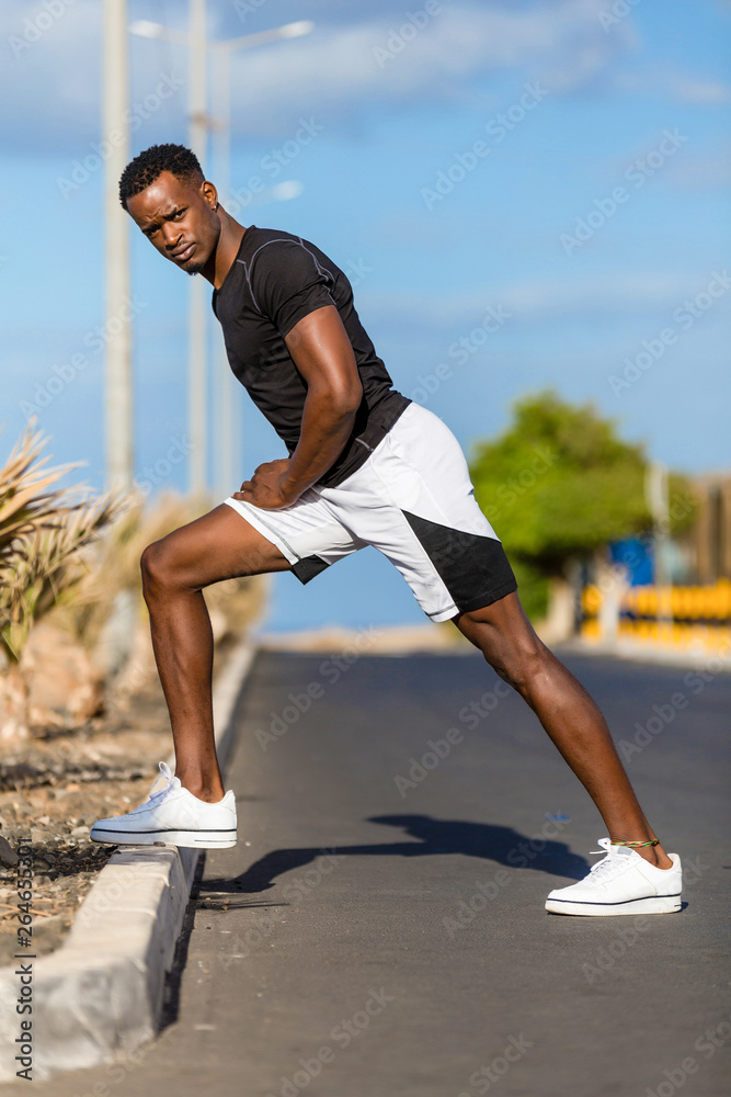 Black african american young man stretching after outdoor jogging