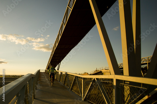 Ciclista cruzando un puente sobre vías del tres