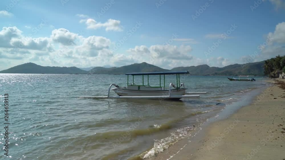 Exotic view of traditional tourism boat on the Elak-Elak beach with white sand, turquoise water, and clear sky in Lombok near Bali, Indonesia. Shot in 4k resolution Exotic view of traditional tourism boat on the Elak-Elak beach with white sand, turquoise water, and clear sky in Lombok near Bali, Indonesia. Shot in 4k resolution