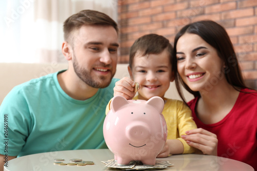 Happy family with piggy bank and money at home