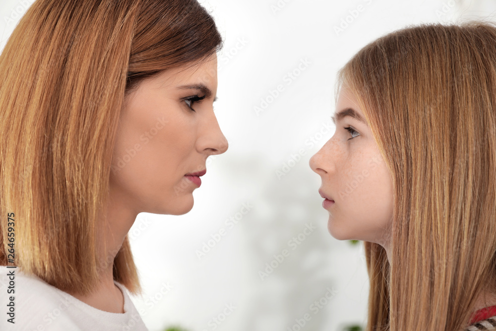 Mother and her teenager daughter looking at each other indoors Mother and her teenager daughter looking at each other indoors