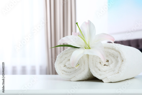 Rolled towels and flower on table in bedroom. Space for text