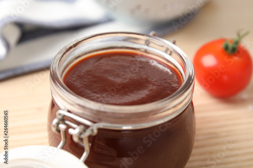 Glass jar of hot barbecue sauce on table, closeup